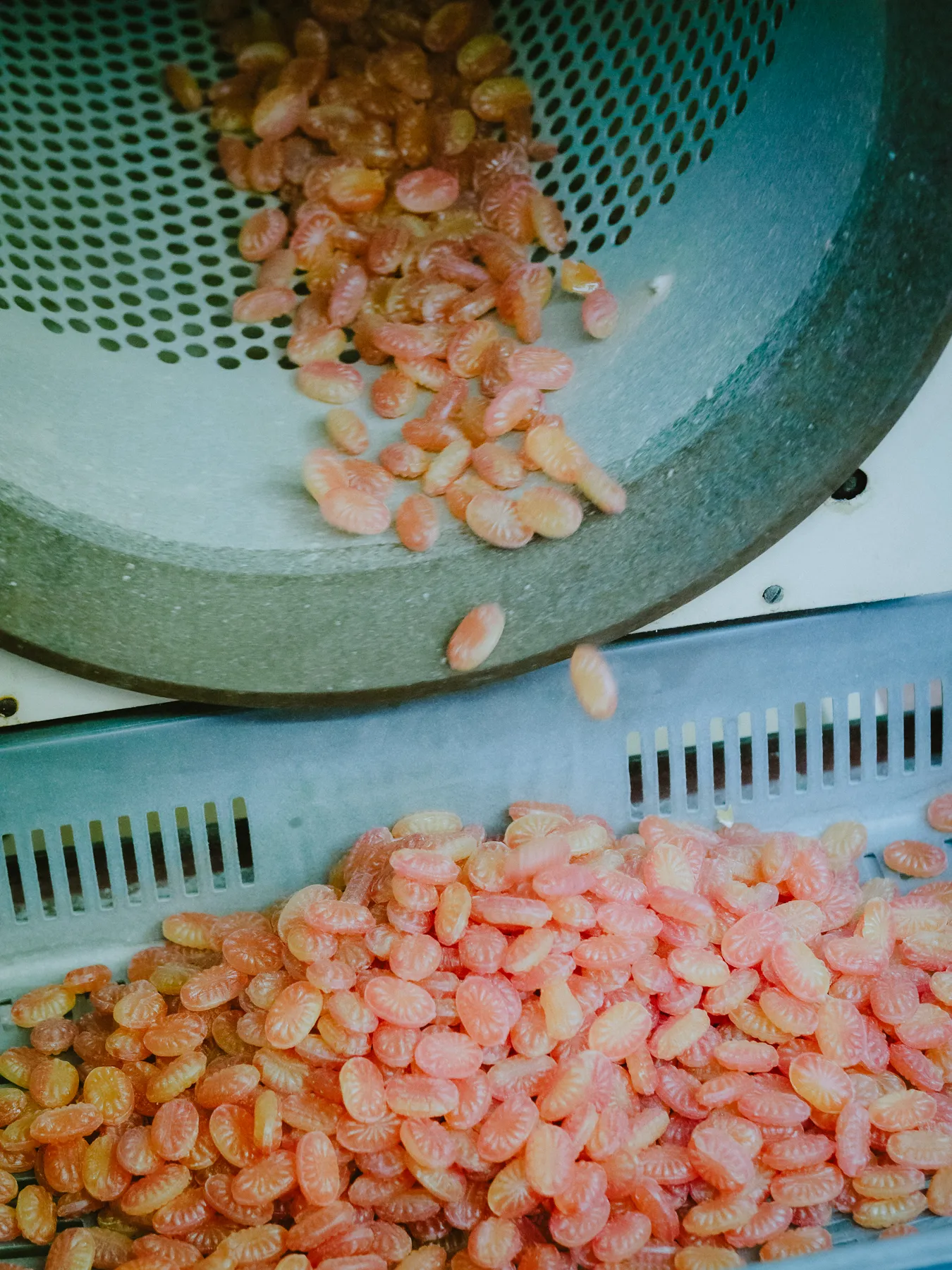 Bonbons purzeln aus der Trommel — frisch poliert nach dem Prägeprozess